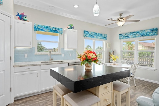 219 Pintail Ln, Rockport, TX 78382 - kitchen with a sink, a kitchen bar, light wood-style floors, decorative backsplash, and crown molding