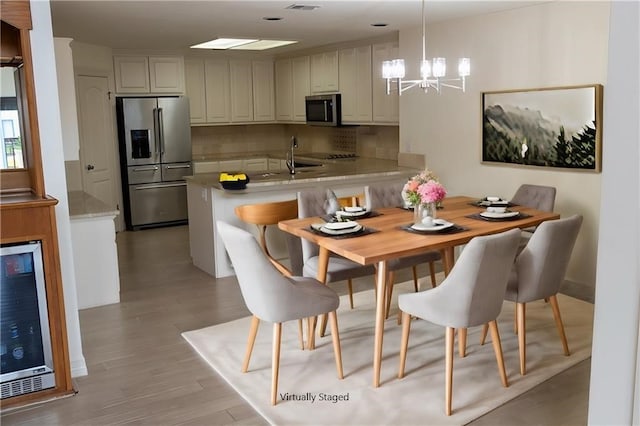 kitchen featuring wine cooler, decorative backsplash, light wood-style flooring, appliances with stainless steel finishes, and a peninsula