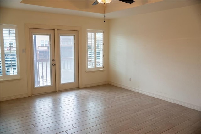 empty room with a ceiling fan, wood finished floors, and baseboards