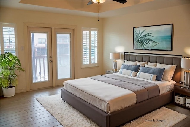 bedroom with wood finished floors, a raised ceiling, a ceiling fan, and access to outside