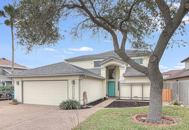 traditional-style house with stucco siding, a tile roof, fence, concrete driveway, and a garage