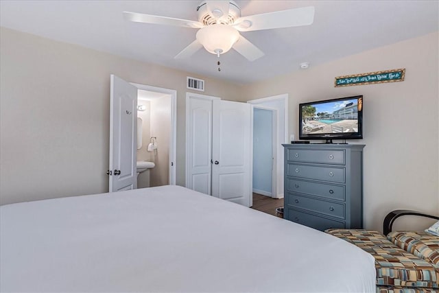 bedroom featuring a ceiling fan, visible vents, connected bathroom, and wood finished floors