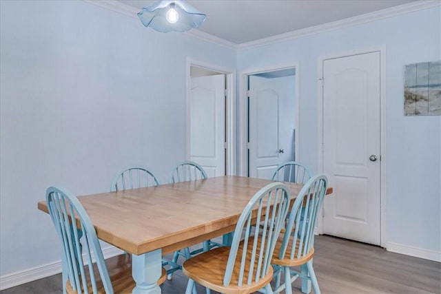 dining room featuring baseboards, wood finished floors, and crown molding