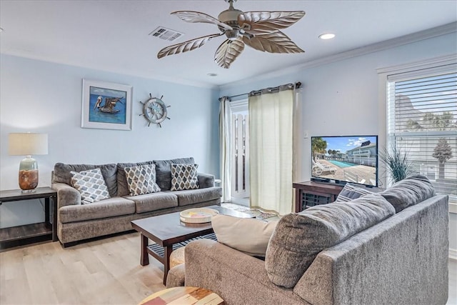 living area featuring ceiling fan, light wood-type flooring, visible vents, and crown molding