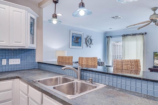 kitchen with a sink, visible vents, white cabinetry, backsplash, and dark countertops