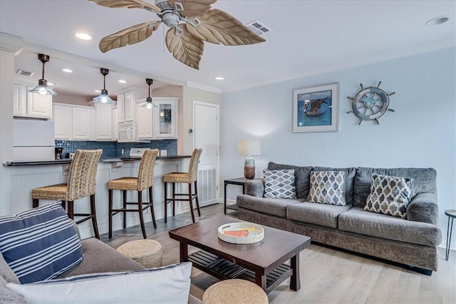 living room with light wood-style floors, ceiling fan, visible vents, and recessed lighting