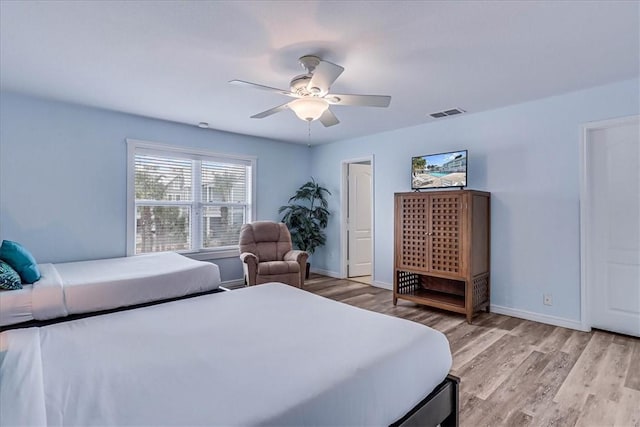 bedroom with light wood-style floors, visible vents, baseboards, and a ceiling fan