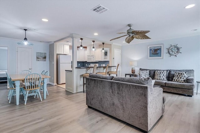 living room featuring ceiling fan, light wood-style flooring, recessed lighting, visible vents, and crown molding