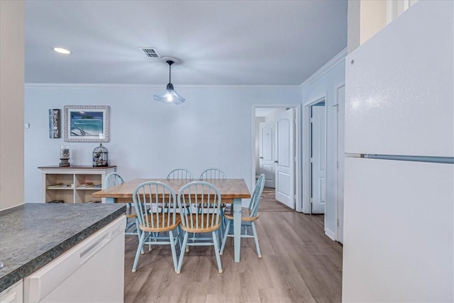 dining room with light wood-type flooring, visible vents, and crown molding