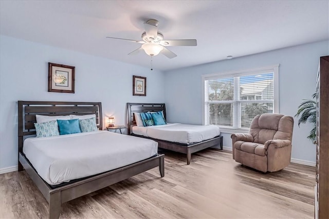 bedroom with light wood finished floors, baseboards, and a ceiling fan