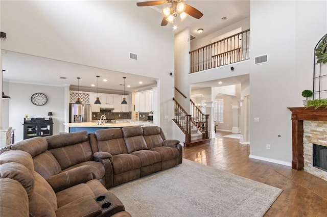 6105 Greenough Ct, Corpus Christi, TX 78414 - living room featuring a stone fireplace, stairway, a ceiling fan, wood finished floors, and arched walkways