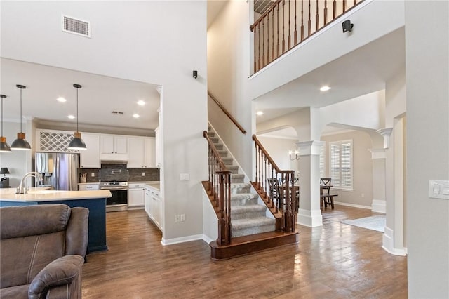 6105 Greenough Ct, Corpus Christi, TX 78414 - living room with decorative columns, a high ceiling, arched walkways, stairs, and recessed lighting