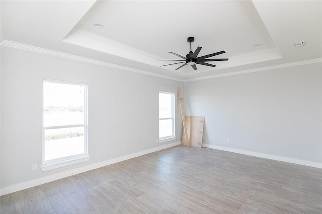 unfurnished room featuring a tray ceiling, light hardwood / wood-style flooring, ceiling fan, and crown molding