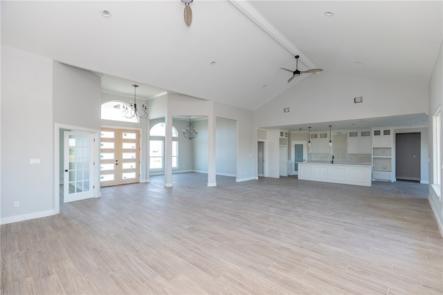 unfurnished living room featuring french doors, light hardwood / wood-style flooring, high vaulted ceiling, and ceiling fan with notable chandelier