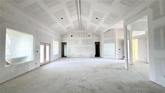 unfurnished living room with high vaulted ceiling