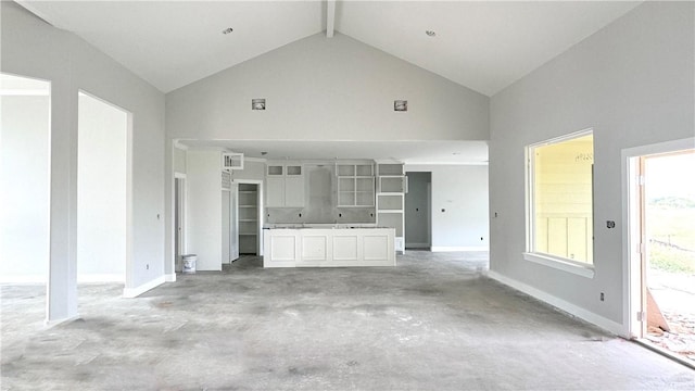 unfurnished living room featuring beam ceiling and high vaulted ceiling