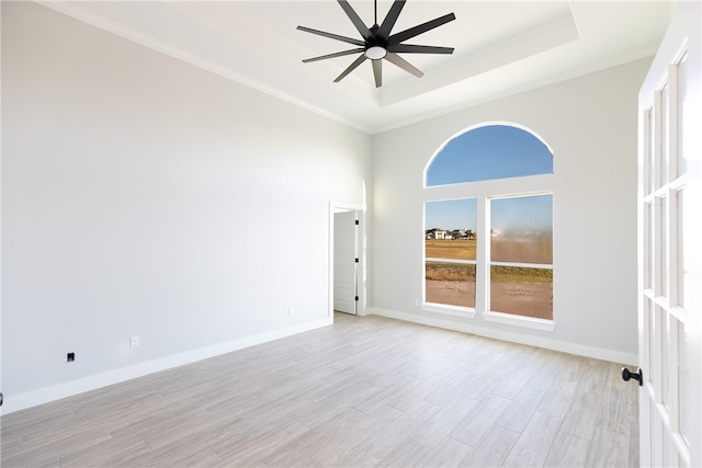 empty room with a tray ceiling, ceiling fan, light hardwood / wood-style flooring, and ornamental molding