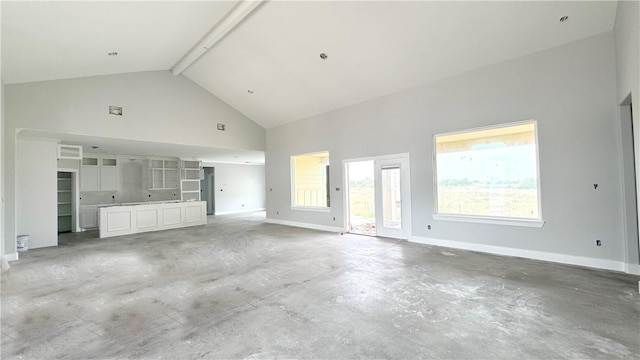 unfurnished living room with beamed ceiling, concrete floors, and high vaulted ceiling