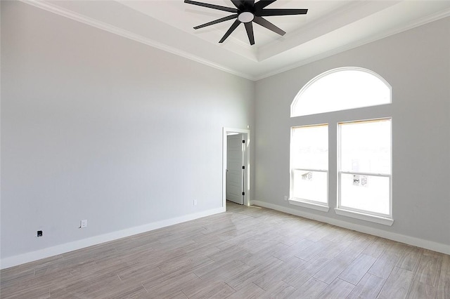 spare room with a towering ceiling, light hardwood / wood-style flooring, ceiling fan, and ornamental molding