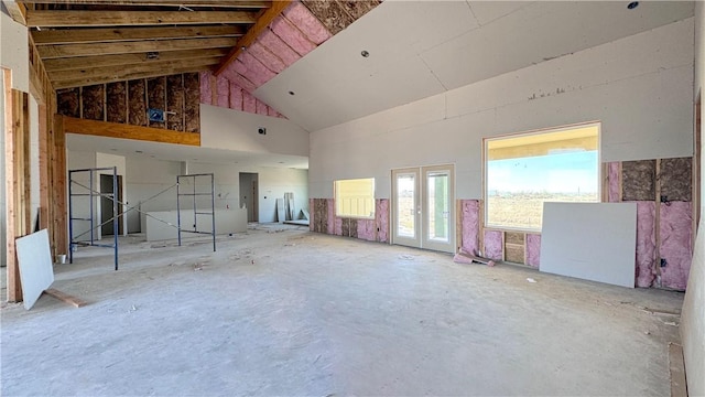 spare room featuring french doors, concrete floors, and high vaulted ceiling