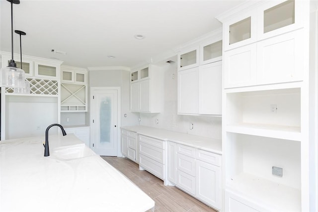 kitchen featuring sink, light stone counters, light hardwood / wood-style flooring, decorative light fixtures, and white cabinets