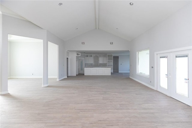 unfurnished living room featuring beam ceiling, french doors, high vaulted ceiling, and light wood-type flooring