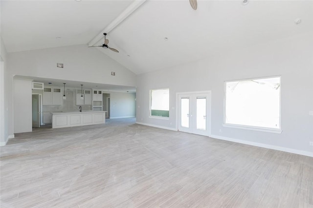 unfurnished living room with ceiling fan, sink, light hardwood / wood-style flooring, high vaulted ceiling, and beamed ceiling