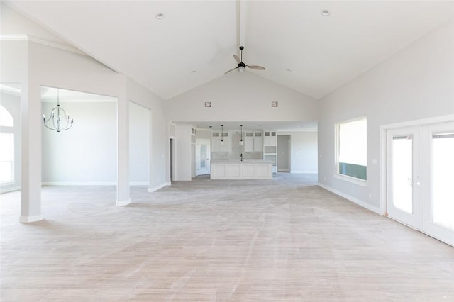 unfurnished living room with ceiling fan with notable chandelier, sink, high vaulted ceiling, and french doors