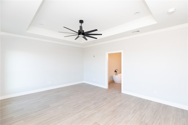 spare room with a raised ceiling, light hardwood / wood-style floors, and ornamental molding