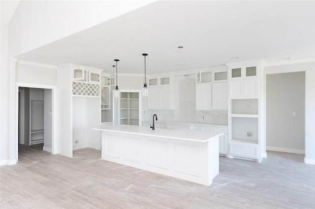 kitchen with white cabinetry, a center island with sink, decorative light fixtures, and light wood-type flooring