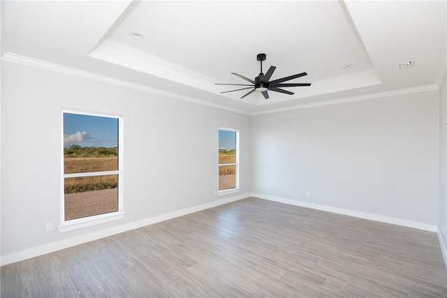 unfurnished room featuring a raised ceiling, light hardwood / wood-style flooring, ceiling fan, and crown molding