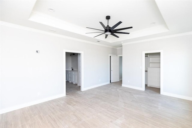 unfurnished bedroom with ceiling fan, a raised ceiling, and ensuite bath