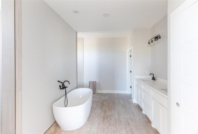 bathroom featuring hardwood / wood-style floors, vanity, and a tub to relax in