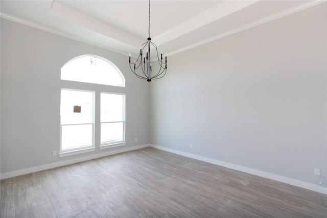 empty room with wood-type flooring, a tray ceiling, an inviting chandelier, and ornamental molding