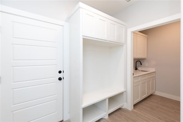 mudroom with sink and light hardwood / wood-style flooring