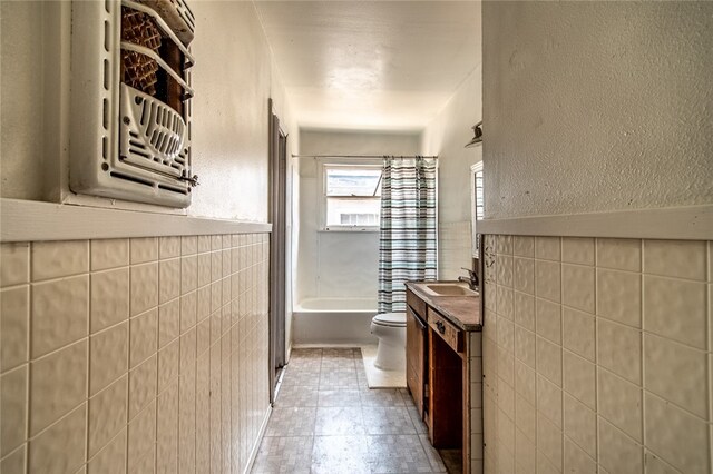 full bathroom featuring tile patterned flooring, shower / bath combination with curtain, vanity, toilet, and tile walls