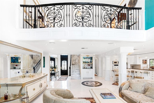 living room with stairway, a high ceiling, and ornate columns