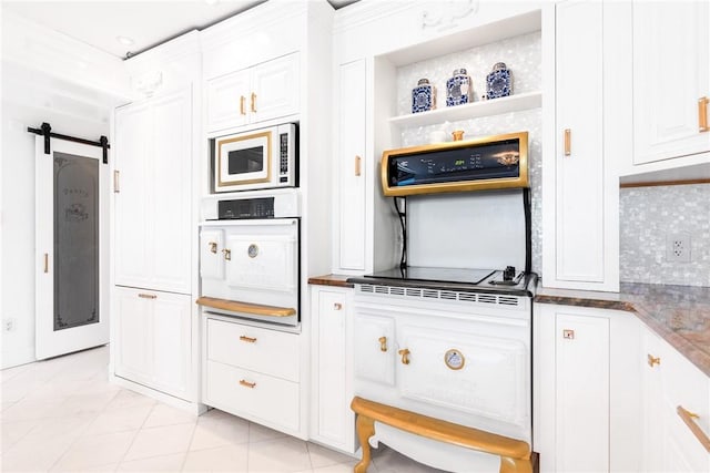 kitchen with a barn door, white appliances, tasteful backsplash, and white cabinets