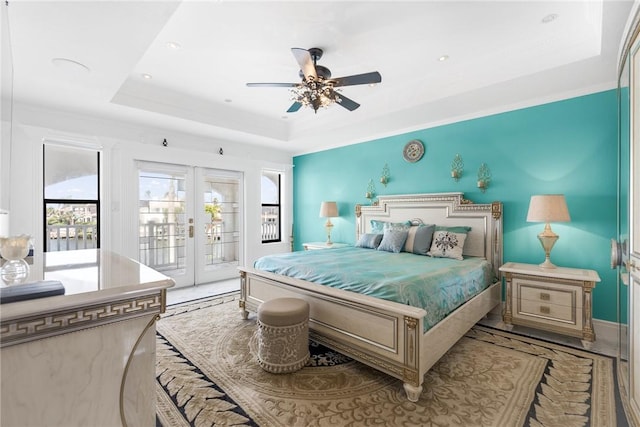 bedroom with a tray ceiling, french doors, ceiling fan, and access to outside