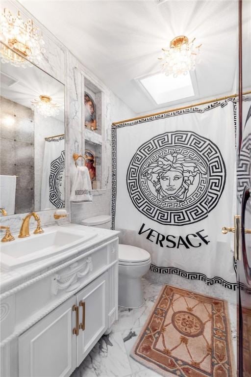 bathroom with vanity, a skylight, toilet, and marble finish floor