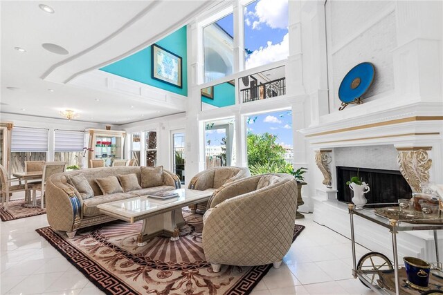 living room featuring a towering ceiling, a fireplace, and tile patterned flooring