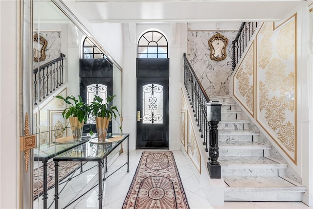 foyer entrance featuring wallpapered walls, stairway, and a high ceiling