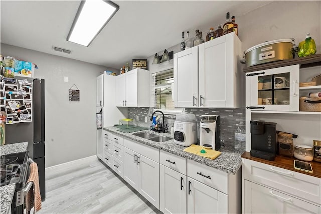 3614 Capri Dr, Corpus Christi, TX 78415 - kitchen with white cabinetry, light wood finished floors, decorative backsplash, stainless steel range oven, and light stone counters