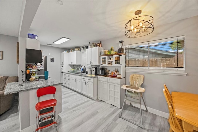 3614 Capri Dr, Corpus Christi, TX 78415 - kitchen featuring light wood-style floors, white cabinets, a breakfast bar, a chandelier, and open shelves