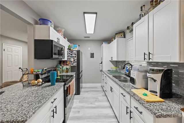 3614 Capri Dr, Corpus Christi, TX 78415 - kitchen with light wood-style flooring, stainless steel range with electric cooktop, decorative backsplash, white cabinets, and light stone countertops