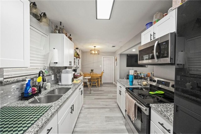 3614 Capri Dr, Corpus Christi, TX 78415 - kitchen with stainless steel appliances, white cabinetry, light wood-type flooring, light stone countertops, and tasteful backsplash