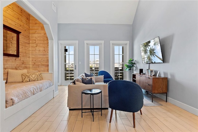 living room with visible vents, baseboards, wood finished floors, and a towering ceiling