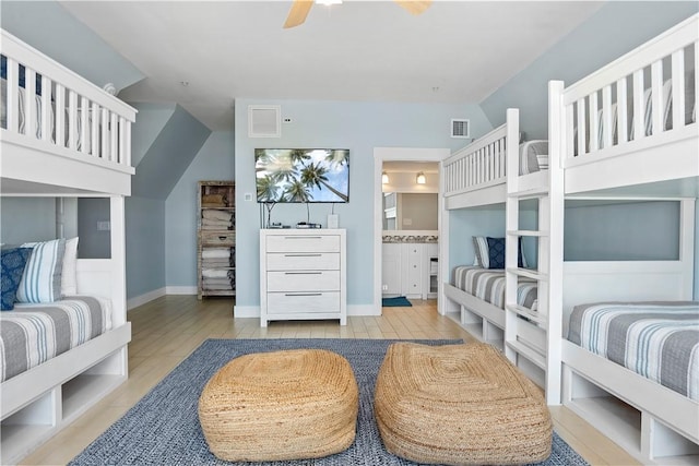 bedroom featuring vaulted ceiling, wood finished floors, visible vents, and connected bathroom