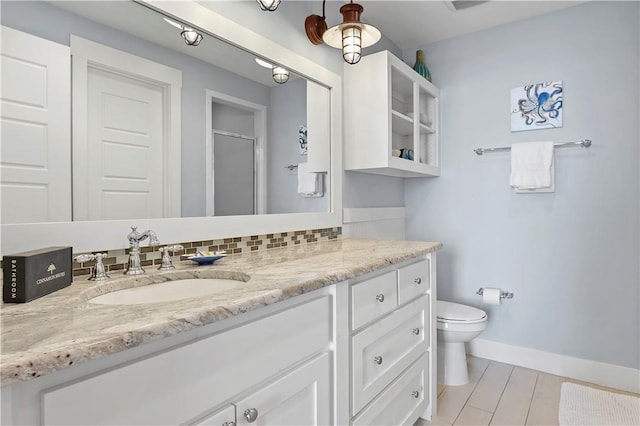 bathroom with vanity, baseboards, a shower stall, toilet, and backsplash