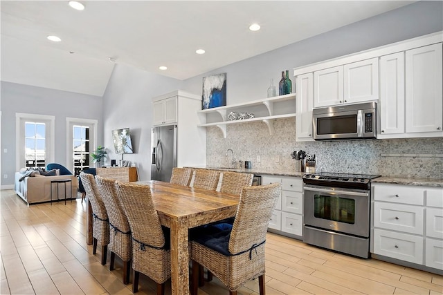 kitchen with open shelves, tasteful backsplash, appliances with stainless steel finishes, and vaulted ceiling